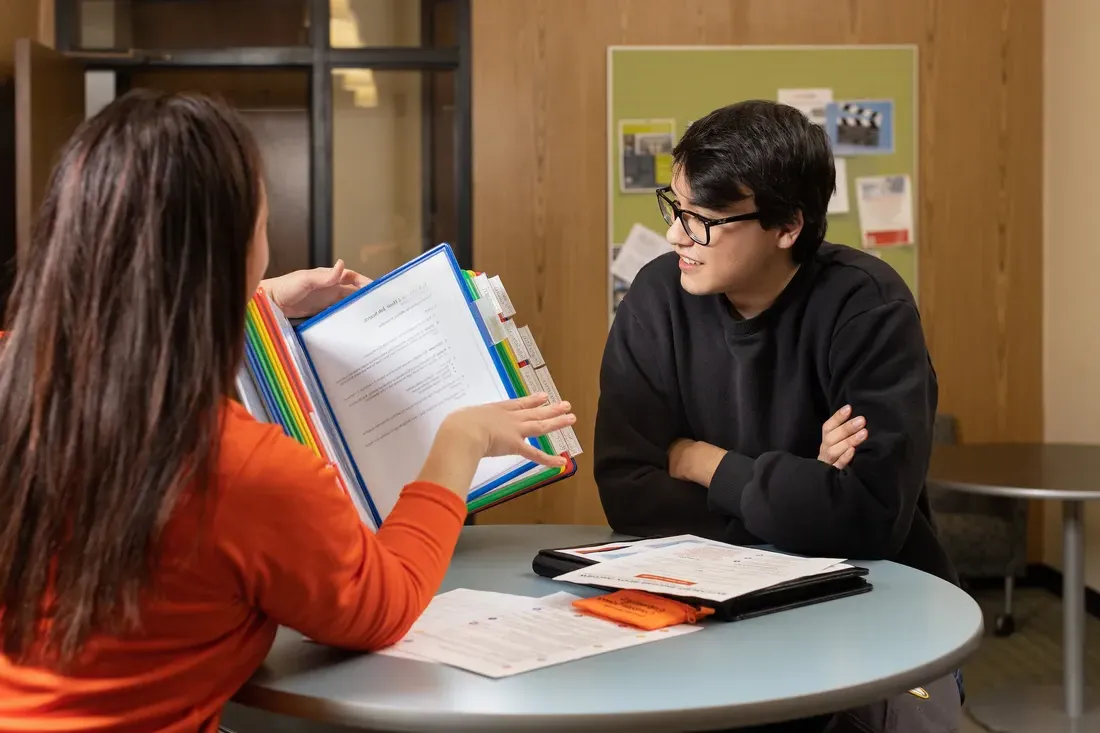 Two people sitting at a table looking through a brochure.